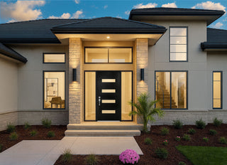 Modern black Framewell front door with horizontal glass inserts, framed by stacked stone columns and large windows on a luxury beige home exterior.