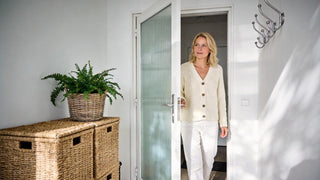 Woman entering bright hallway with wicker storage baskets